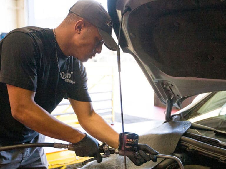 A Don's Quick Lube tech filling fresh oil under the hood
